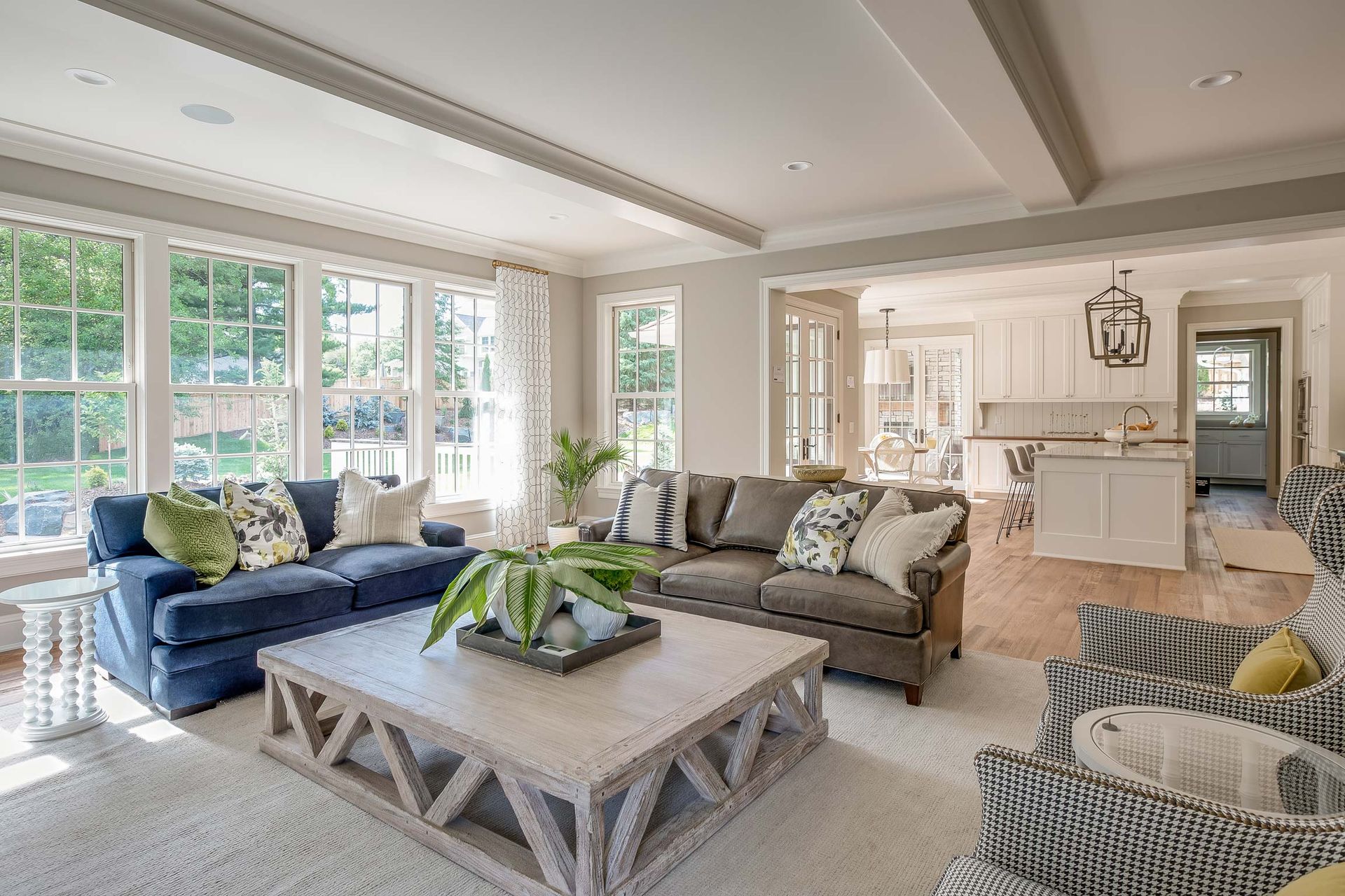 Living room with blue and gray sofas, large windows, and an open view to the kitchen.